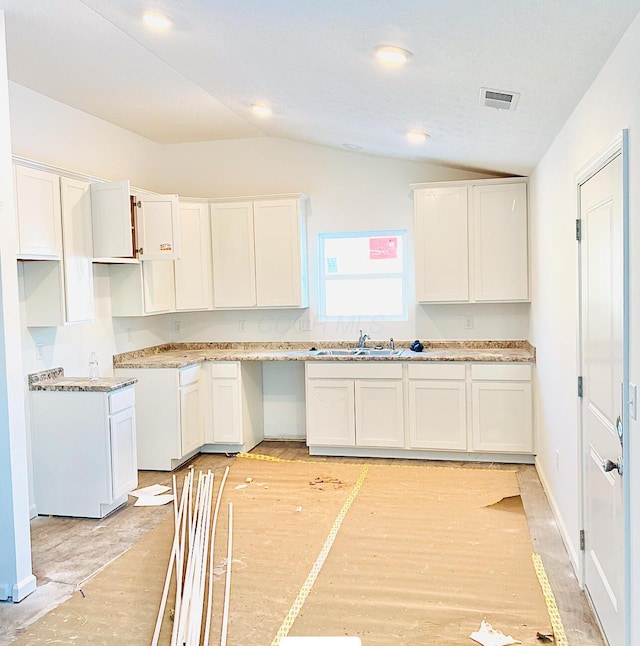 kitchen featuring white cabinetry, lofted ceiling, and sink