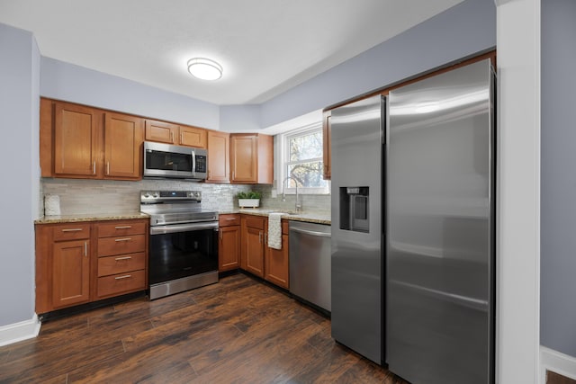 kitchen featuring light stone countertops, appliances with stainless steel finishes, tasteful backsplash, and dark wood-type flooring