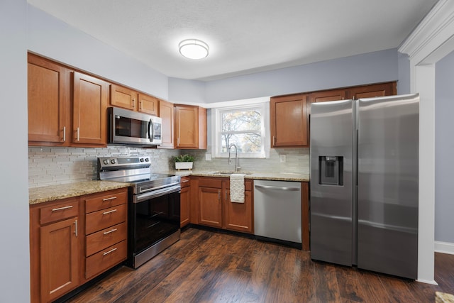 kitchen with backsplash, light stone counters, sink, and stainless steel appliances