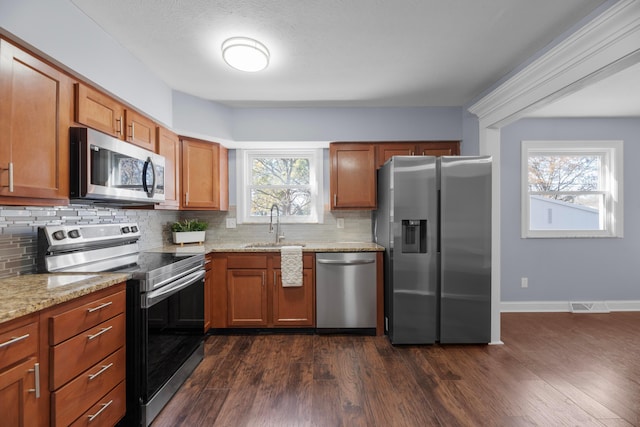 kitchen with backsplash, light stone countertops, sink, and appliances with stainless steel finishes