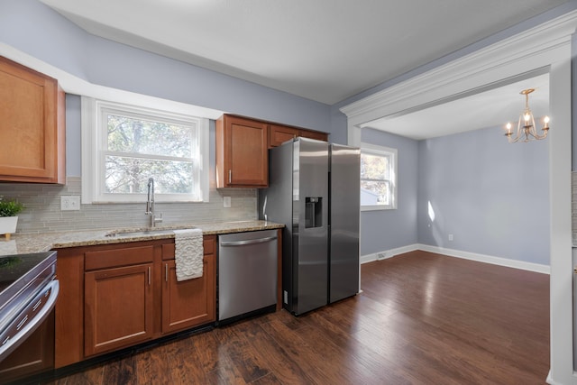 kitchen featuring appliances with stainless steel finishes, tasteful backsplash, an inviting chandelier, and sink