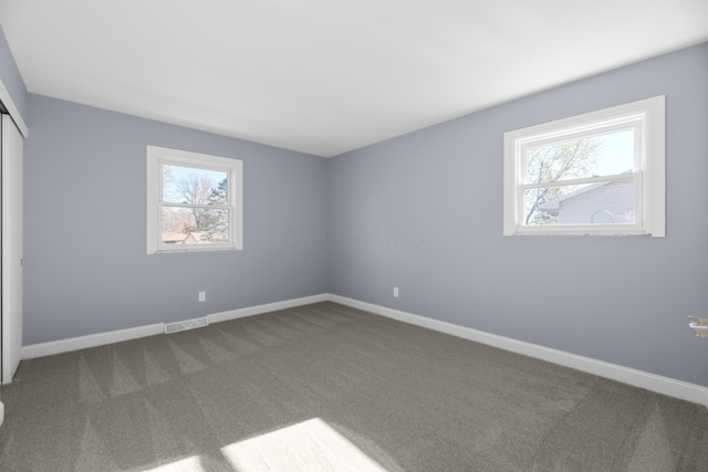 unfurnished bedroom with dark colored carpet and a closet