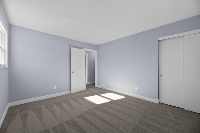 unfurnished bedroom featuring light carpet and a closet