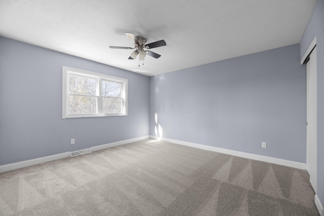 empty room featuring ceiling fan and light colored carpet