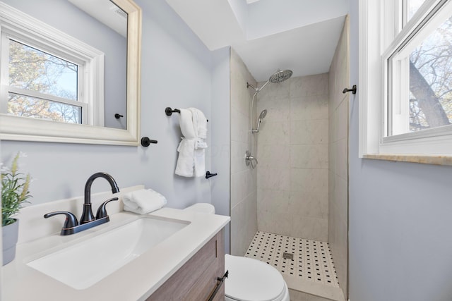 bathroom with tiled shower, vanity, and toilet