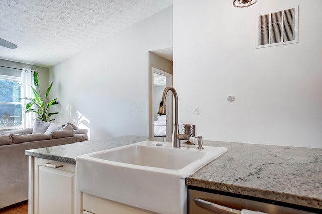 kitchen with a textured ceiling, sink, wood-type flooring, dishwasher, and white cabinetry