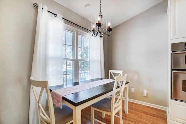 dining area with light hardwood / wood-style flooring and a chandelier