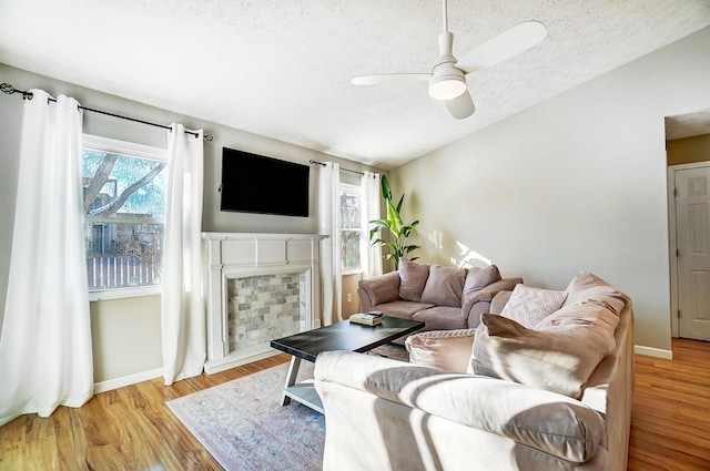 living room with lofted ceiling, ceiling fan, light hardwood / wood-style floors, and a textured ceiling