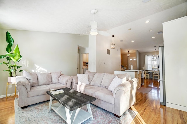 living room featuring ceiling fan, sink, light hardwood / wood-style floors, and lofted ceiling