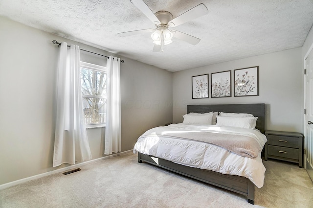 carpeted bedroom featuring a textured ceiling and ceiling fan