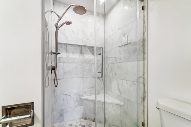 bathroom with a shower with shower door and toilet