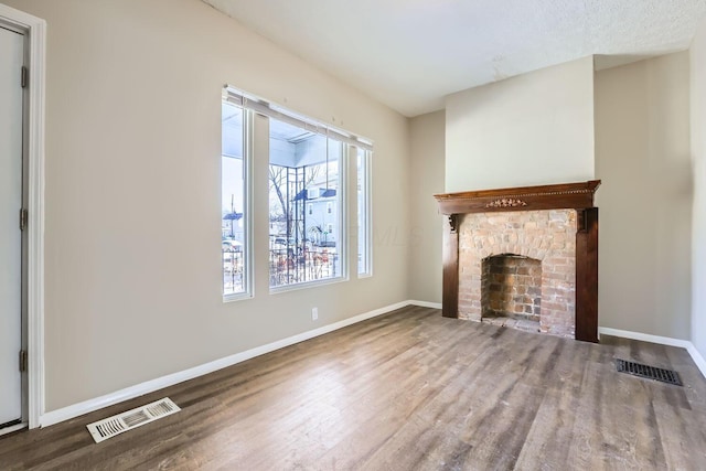 unfurnished living room with hardwood / wood-style floors and a brick fireplace