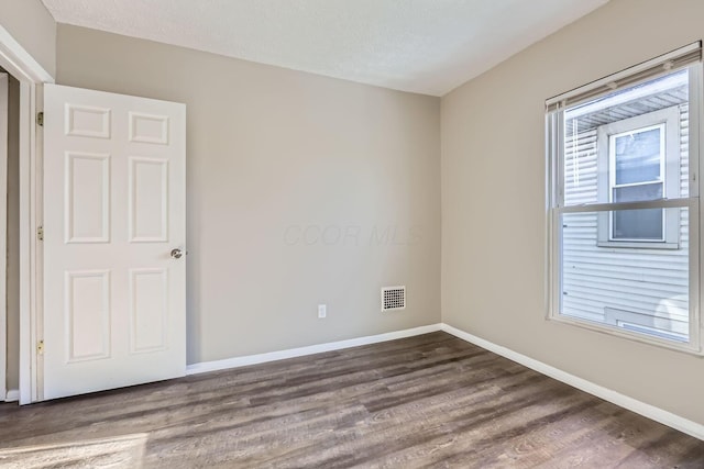 spare room featuring dark wood-type flooring and a textured ceiling