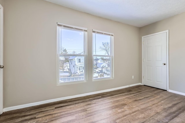 spare room featuring dark hardwood / wood-style floors and a textured ceiling