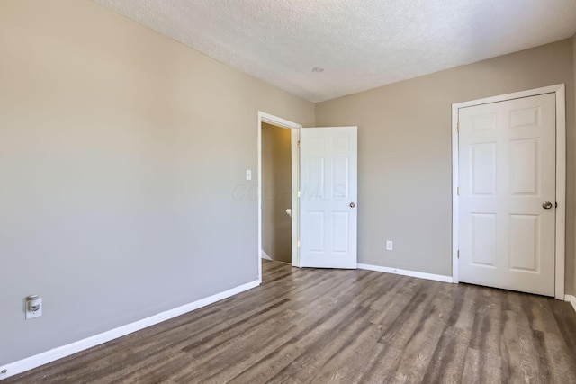 unfurnished bedroom with dark wood-type flooring and a textured ceiling