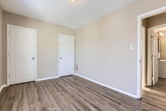 unfurnished bedroom featuring dark wood-type flooring and a textured ceiling