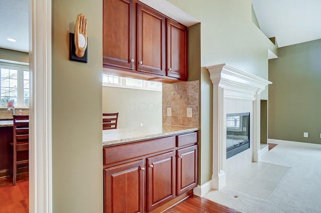 kitchen featuring light stone countertops, light hardwood / wood-style floors, and a tiled fireplace