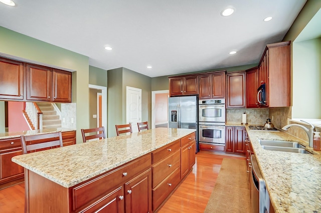 kitchen featuring light stone countertops, a kitchen breakfast bar, stainless steel appliances, sink, and a center island