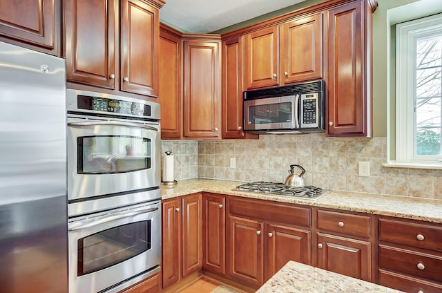 kitchen featuring backsplash, light stone countertops, and appliances with stainless steel finishes