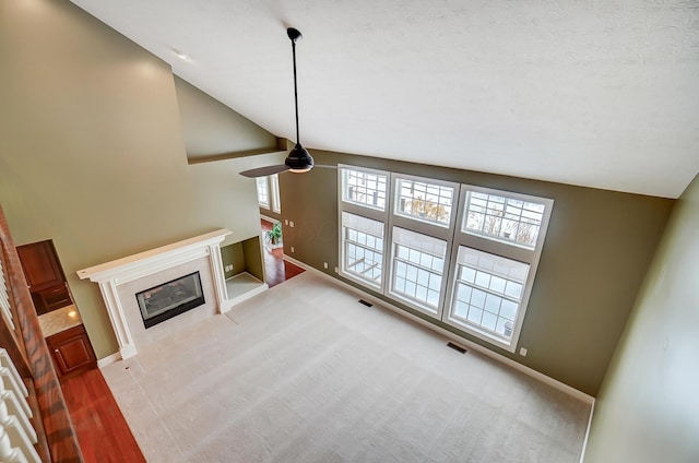 unfurnished living room with light carpet, a textured ceiling, plenty of natural light, and ceiling fan