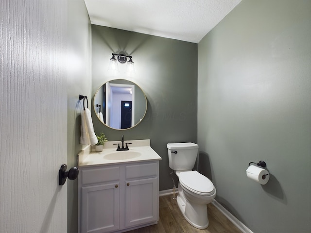 bathroom with hardwood / wood-style floors, vanity, toilet, and a textured ceiling