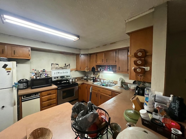 kitchen featuring stainless steel electric range oven, sink, kitchen peninsula, white fridge, and a textured ceiling