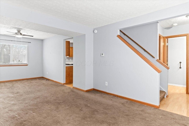 spare room with ceiling fan, light colored carpet, and a textured ceiling