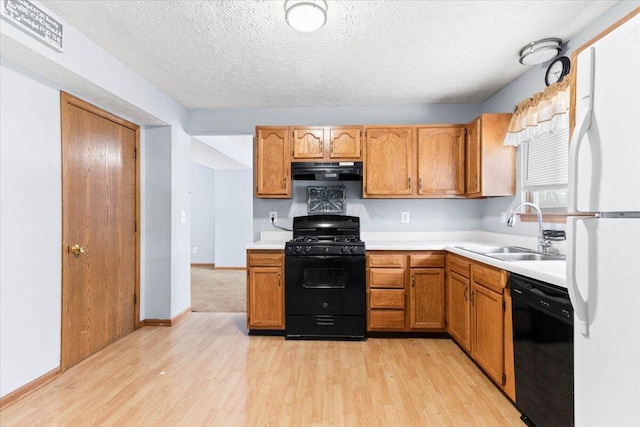 kitchen featuring sink, black appliances, a textured ceiling, and light wood-type flooring