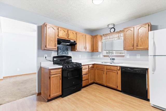 kitchen featuring sink, black appliances, a textured ceiling, and light hardwood / wood-style floors