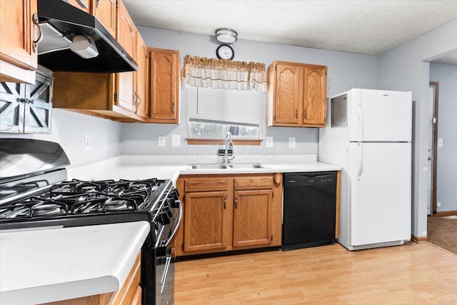 kitchen with black appliances, light wood-type flooring, sink, and a textured ceiling