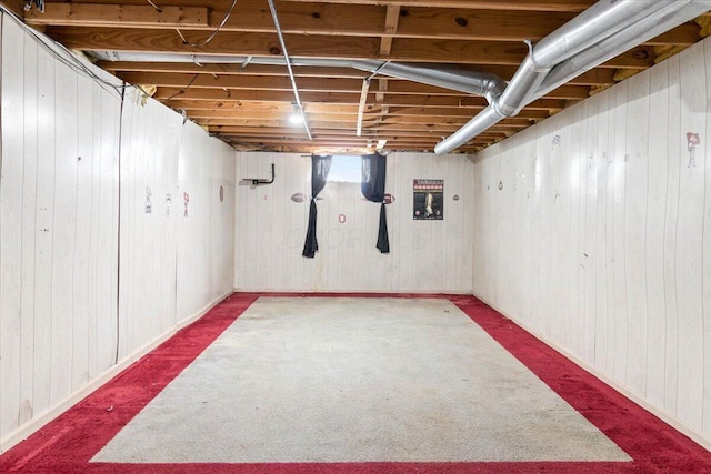 basement featuring carpet and wood walls