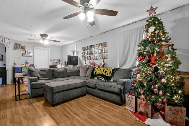 living room with a textured ceiling, light wood-type flooring, and ceiling fan