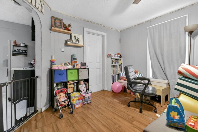 office space featuring hardwood / wood-style floors, ceiling fan, a textured ceiling, and wooden walls