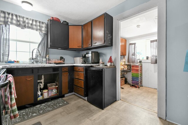 kitchen with a textured ceiling, refrigerator, and sink