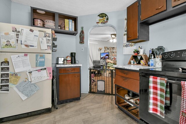 kitchen featuring electric range, ceiling fan, white refrigerator, a textured ceiling, and exhaust hood