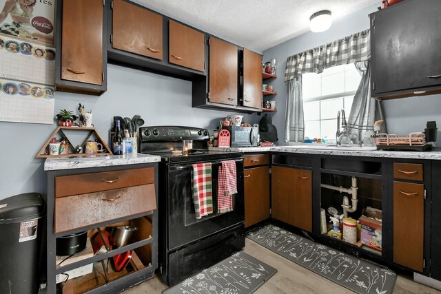 kitchen featuring a textured ceiling, black / electric stove, and sink