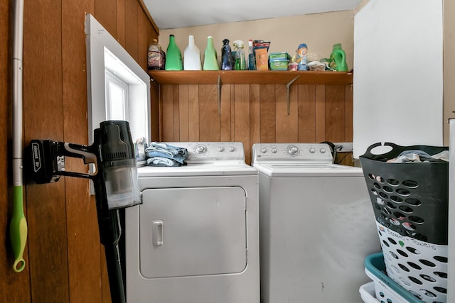 laundry room with wood walls and washer and dryer