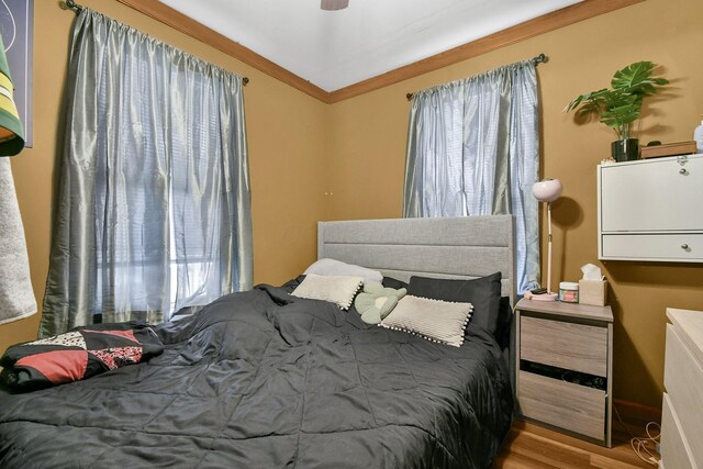 bedroom featuring multiple windows, light wood-type flooring, ceiling fan, and crown molding