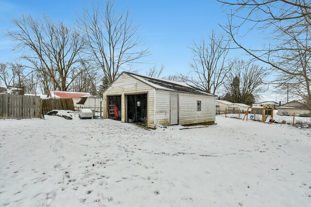 snow covered structure with a garage and a playground