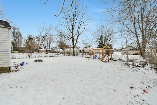 snowy yard with a playground and a fire pit