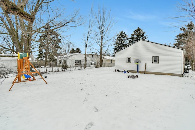 yard layered in snow with a playground and a fire pit