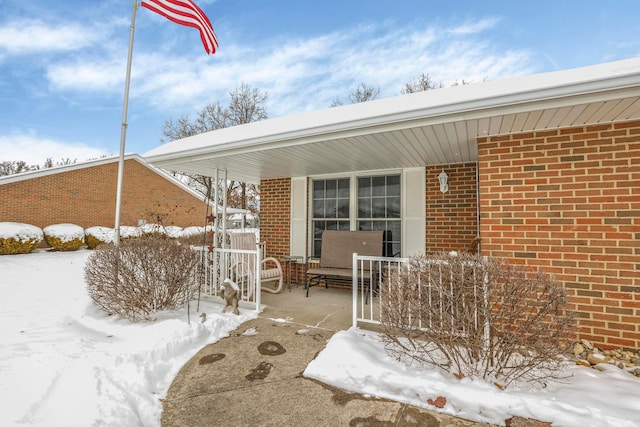 snow covered patio featuring a porch