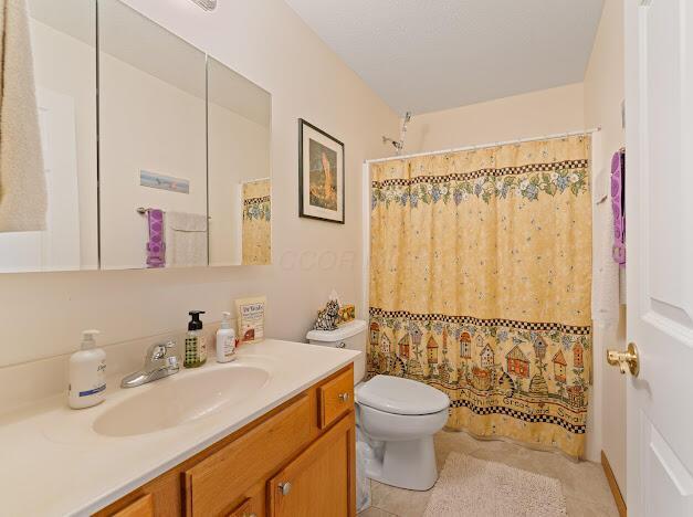 bathroom featuring tile patterned floors, a shower with curtain, vanity, and toilet