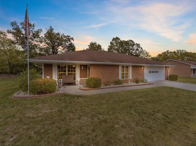 single story home featuring a yard, covered porch, and a garage