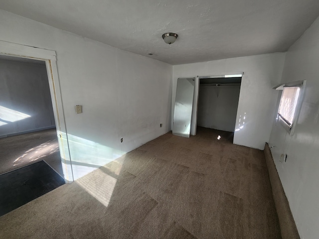 unfurnished bedroom with dark colored carpet and a closet