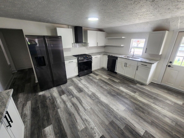 kitchen with black appliances, white cabinets, wall chimney range hood, and sink