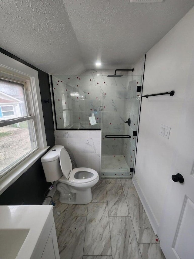 bathroom featuring vanity, vaulted ceiling, toilet, a textured ceiling, and a tile shower