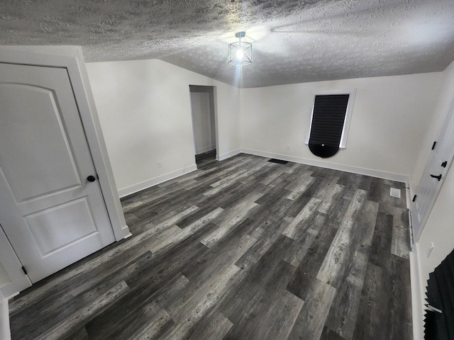 interior space with a textured ceiling, vaulted ceiling, and dark wood-type flooring