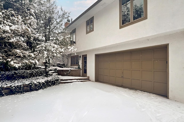 view of snowy exterior with a garage