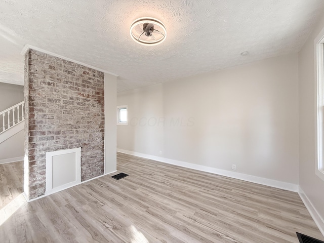 unfurnished living room with a textured ceiling and light wood-type flooring